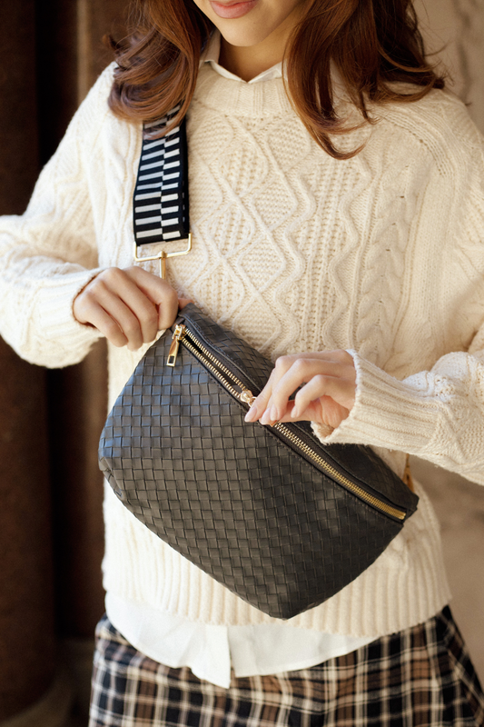 Woman unzipping a gold zipper on a black faux quilted Modern + Chic Rory Oversized Belt Bag for Women – Vegan Leather