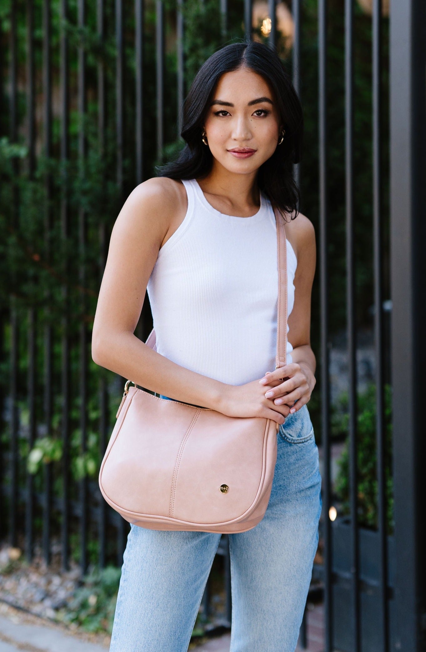 A woman wearing a dusty blush crossbody.