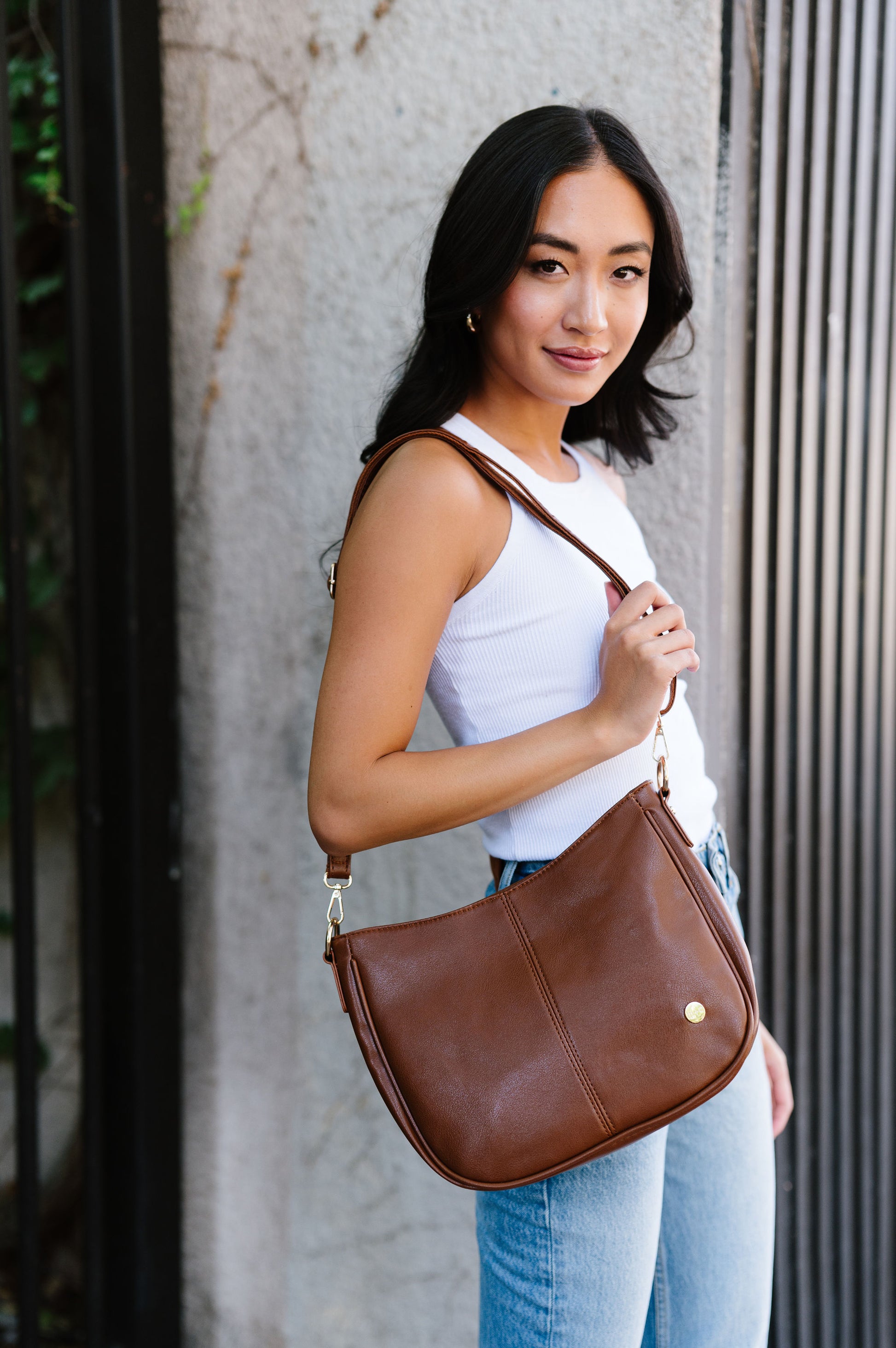 A woman wearing a brown handbag on her shoulder.