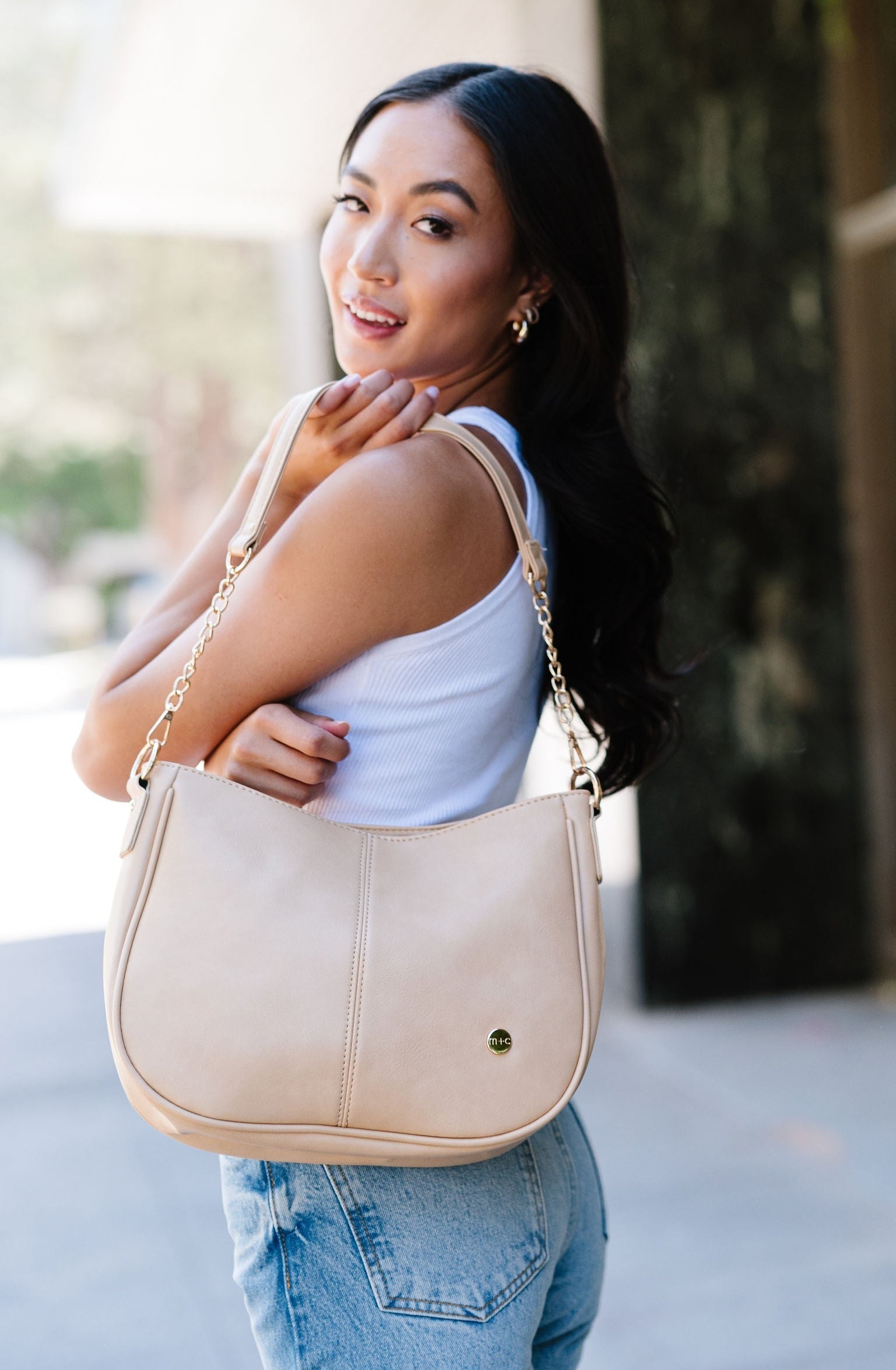 A woman wearing a cream crossbody.
