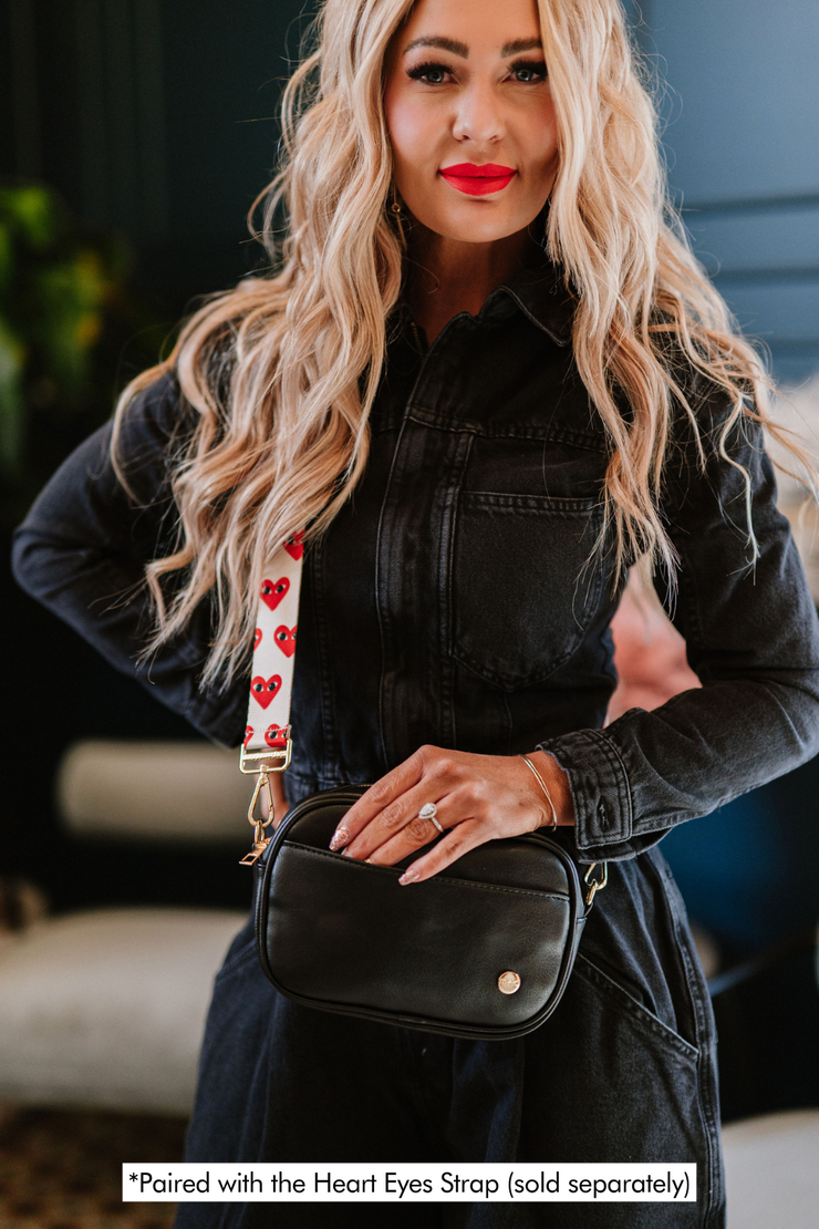 A woman wearing a black crossbody bag paired with the Heart Eyes Strap (sold separately).