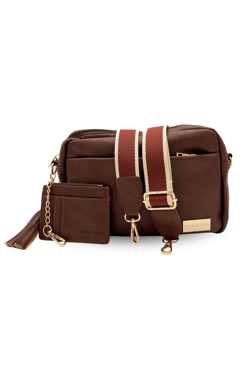 A coffee colored Modern + Chic Alice Crossbody vegan leather bag displaying included key leash, matching wallet and removable tassel. 