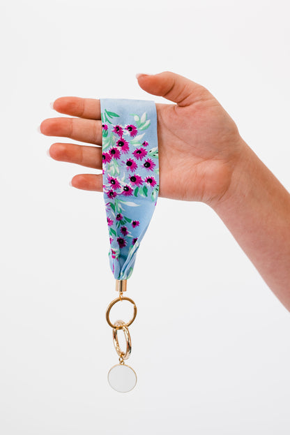 A hand holding Modern + Chic Luna Fabric Keychain Bracelet for Women in front of a white background.