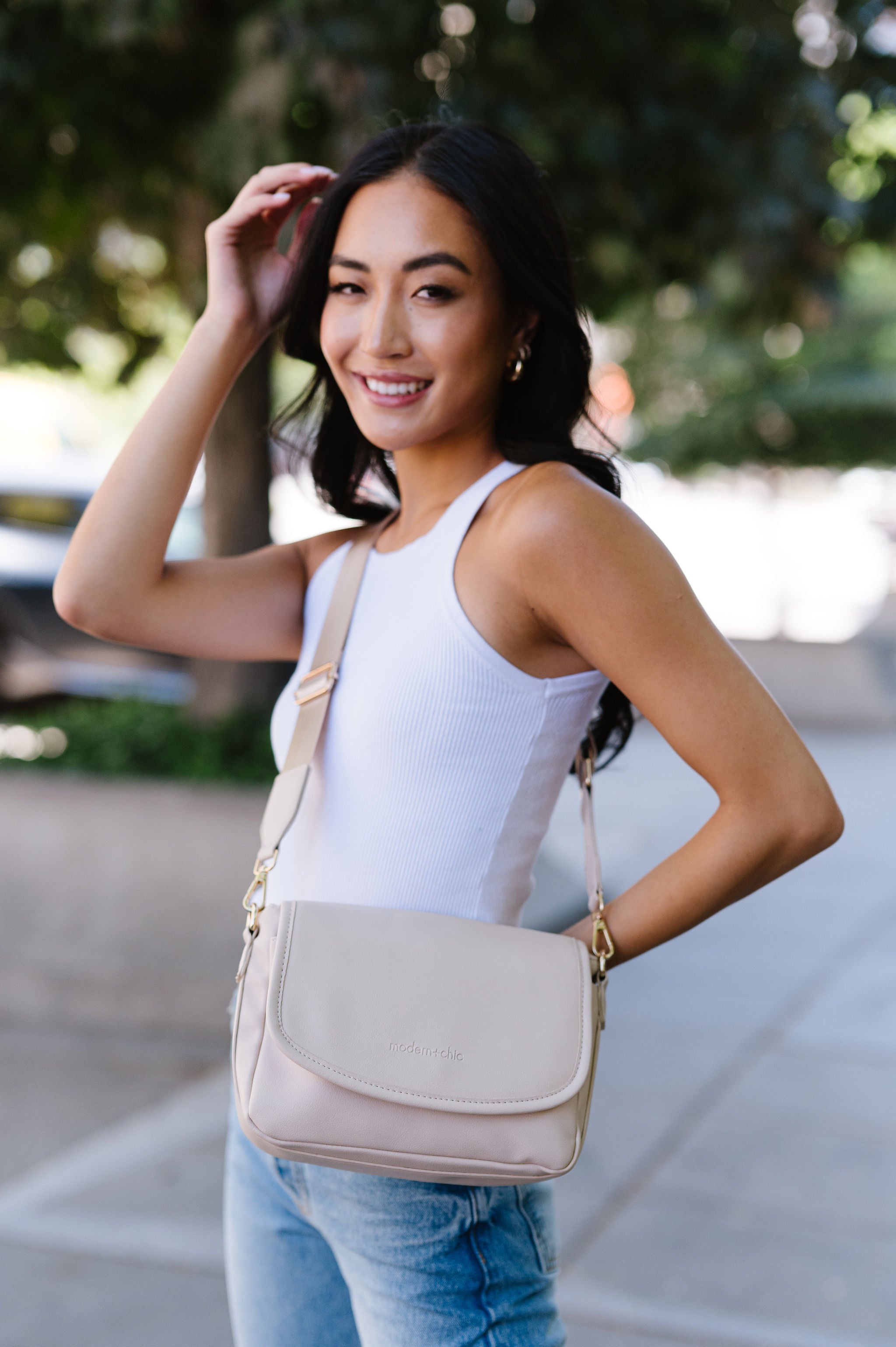 A woman wearing a cream crossbody.