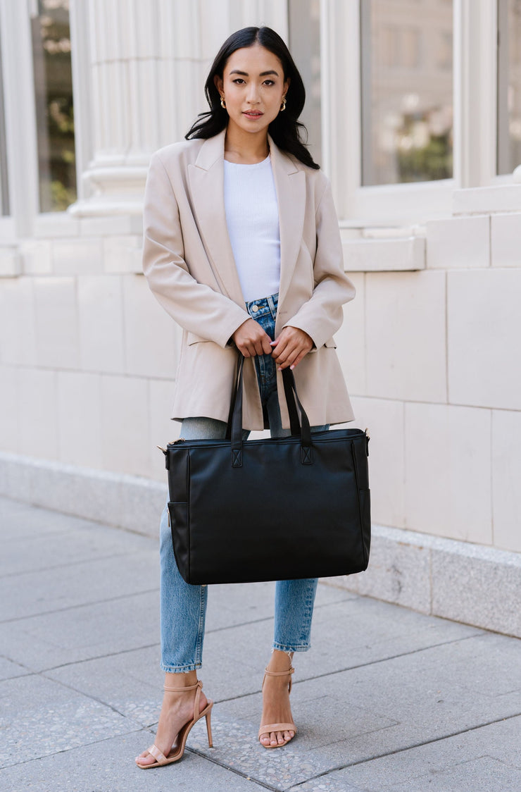 A woman holding a black tote.