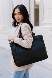 A woman wearing a black tote bag on her shoulder.