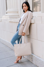 A woman holding a cream tote.