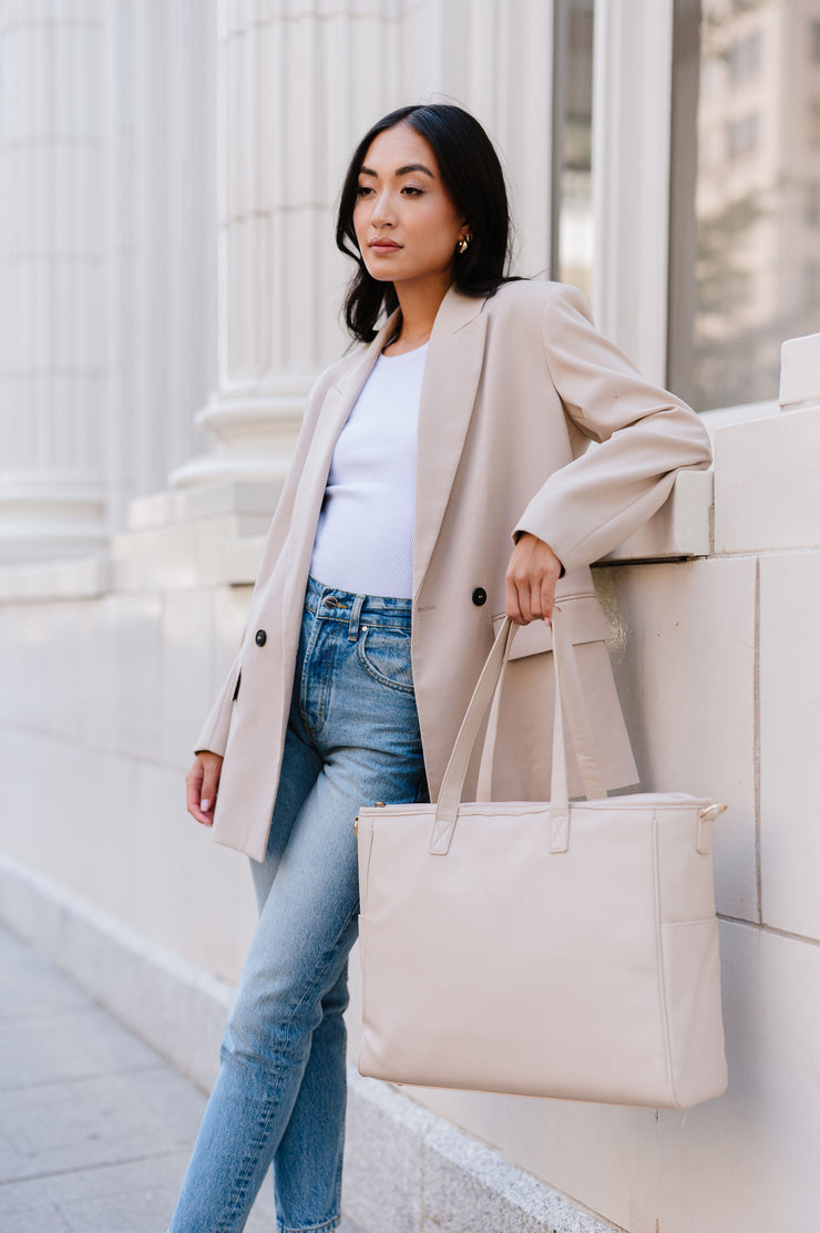 A woman holding a cream tote with the modern+chic logo on the front.