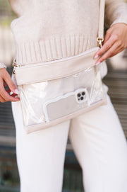 A woman wearing a clear crossbody bag with an iPhone inside.