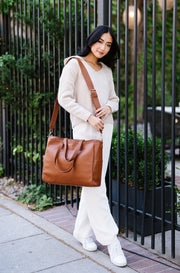 A woman wearing a brown tote on her shoulder.