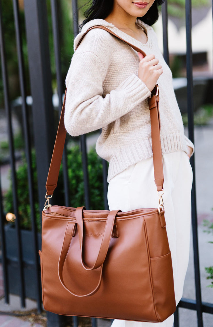 A woman wearing a brown tote on her shoulder.