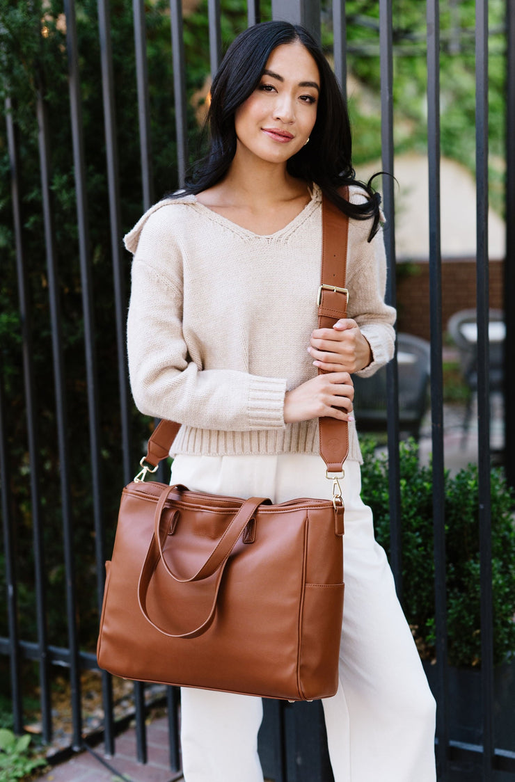 A woman wearing a brown tote crossbody style.