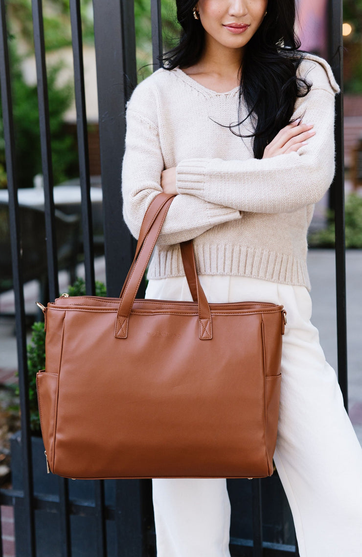 A woman wearing a brown tote on her arm.