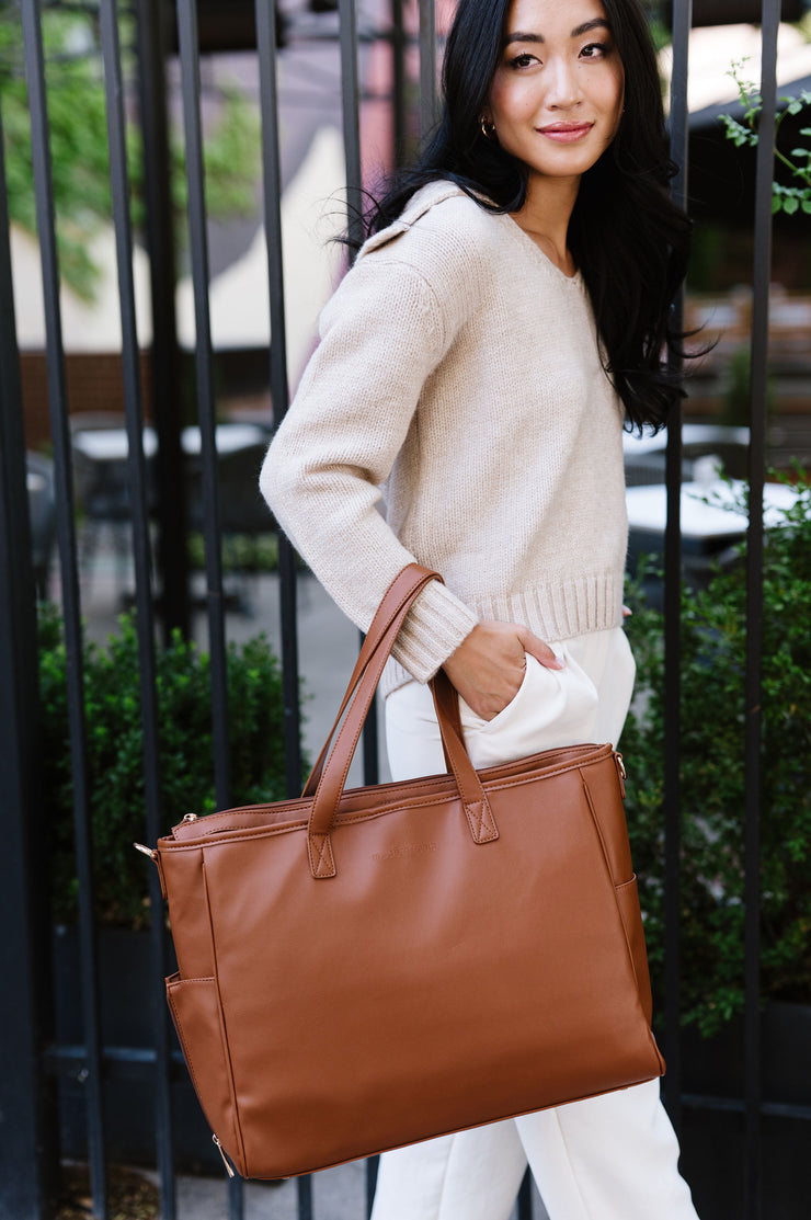 A woman wearing a brown tote on her arm.