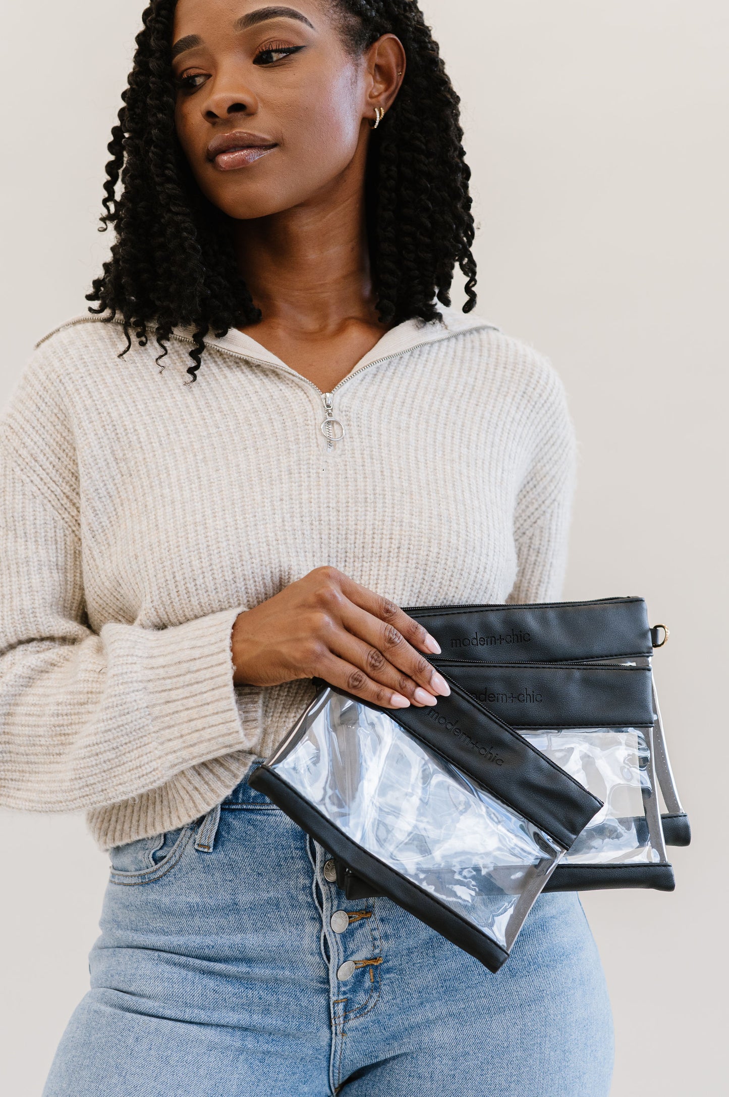 A woman holding a set of three clear bags.