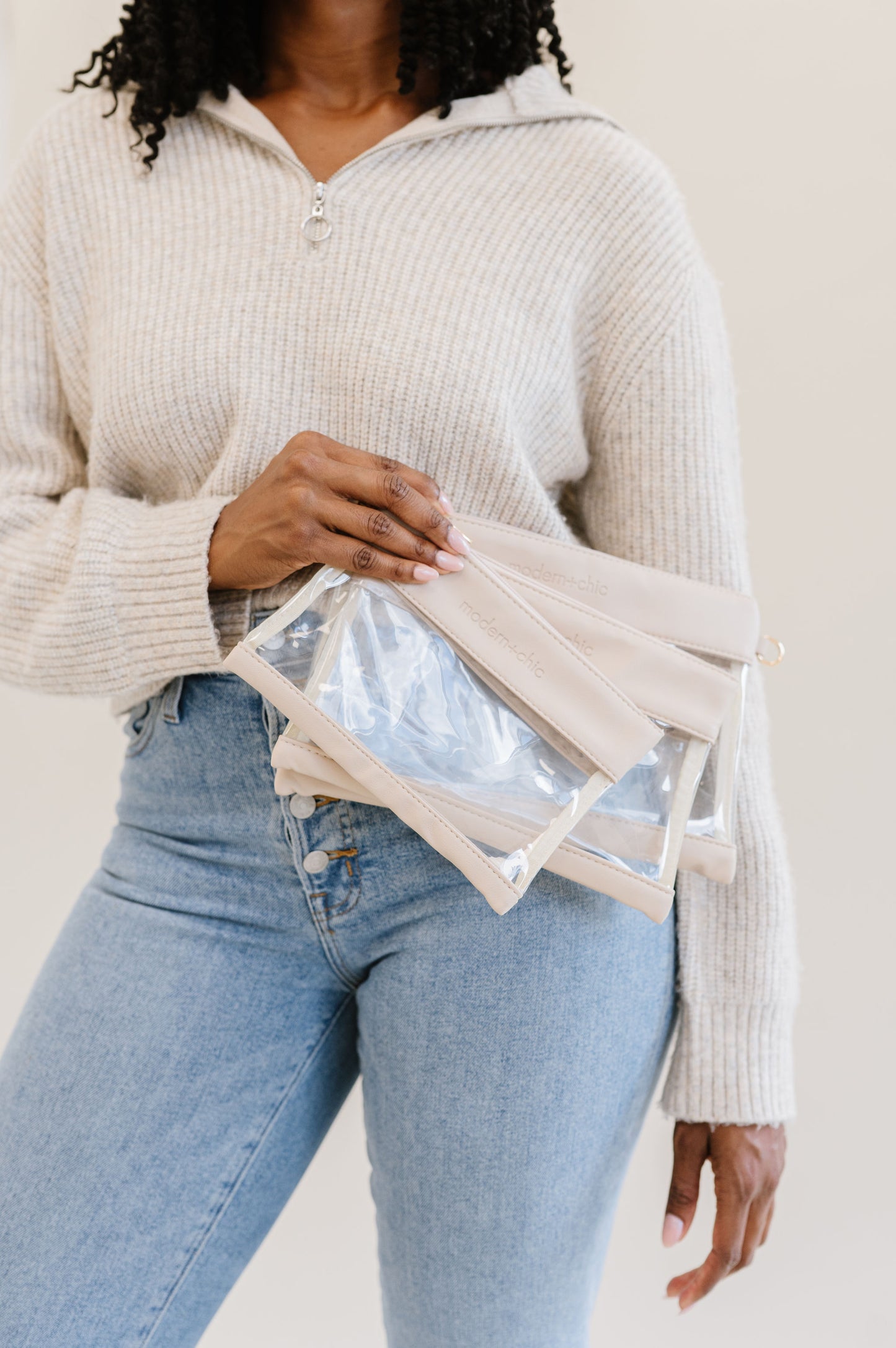 A woman holding three clear bags of varying sizes.