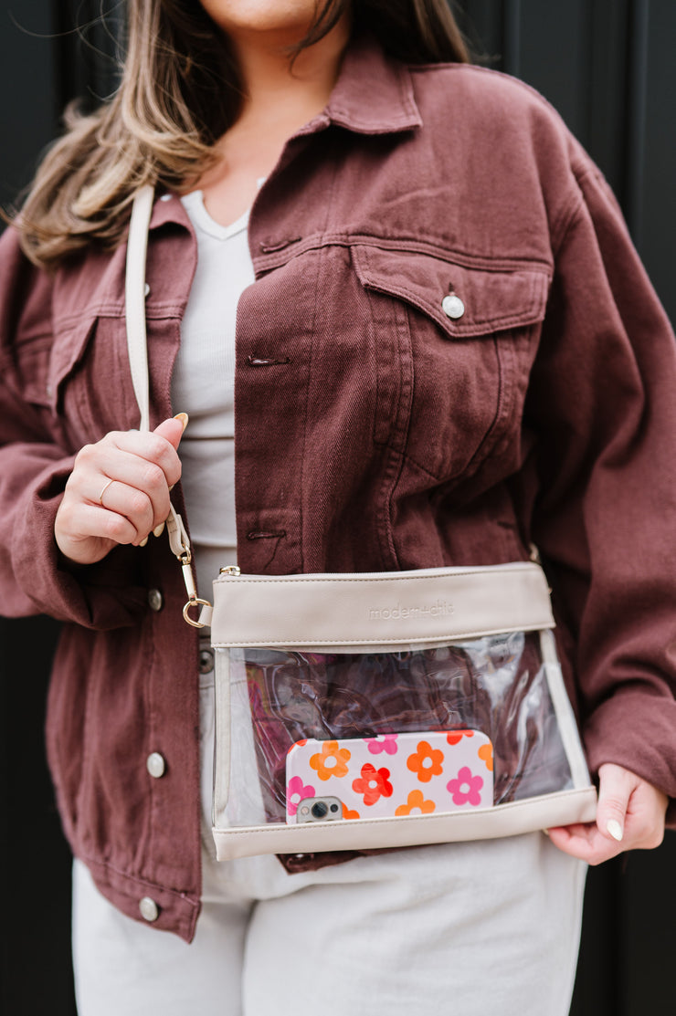 A woman wearing a clear stadium bag with an iPhone inside it.