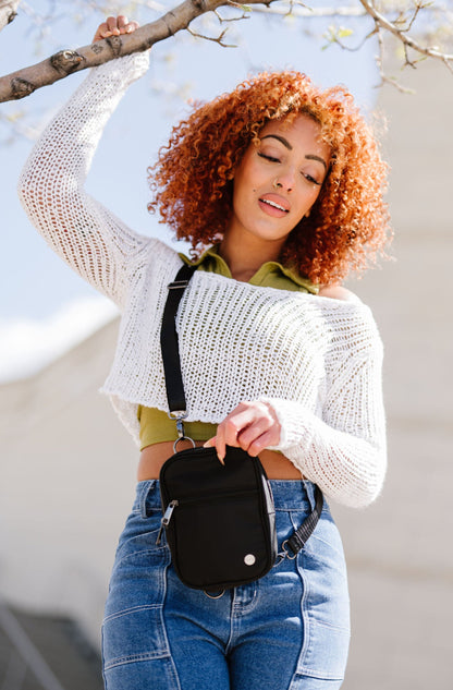 A woman wearing a black Lainey Convertible Crossbody bag with silver hardware, crossbody with an adjustable strap.