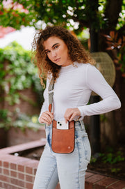 A woman wearing a small brown crossbody bag with a woven strap