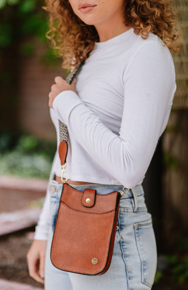 A woman wearing a small brown crossbody bag with a woven strap