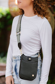 A woman wearing a small black crossbody bag with a woven strap