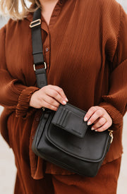 A woman wearing a black crossbody bag and matching wallet.