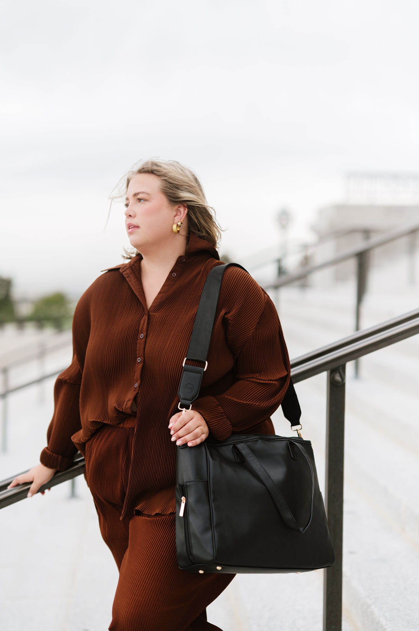 A woman wearing a black tote on her shoulder.