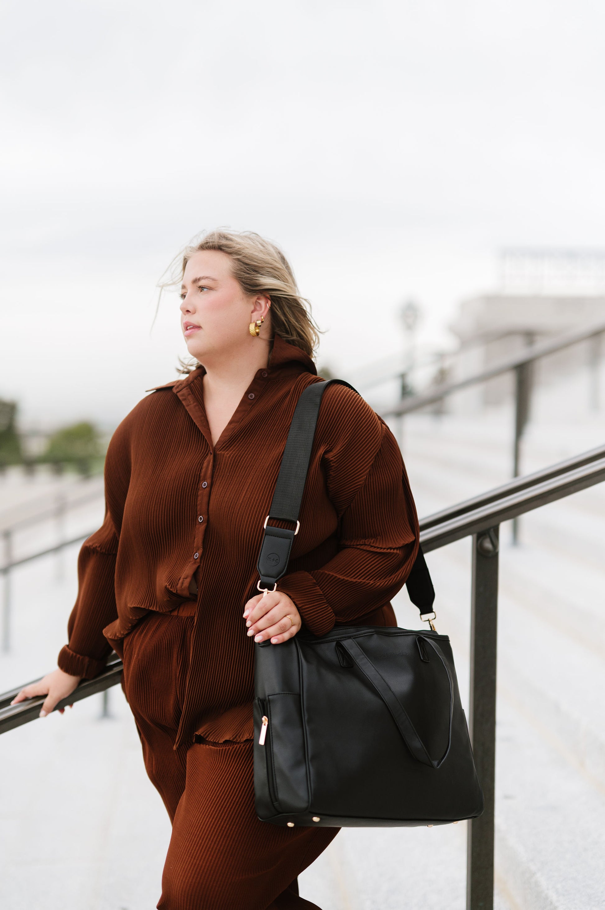 A woman wearing a black tote on her shoulder.