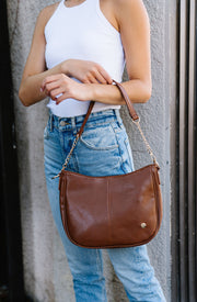 A woman wearing a brown handbag on her arm.