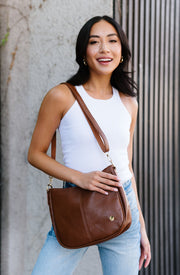 A woman wearing a brown handbag on her shoulder. 