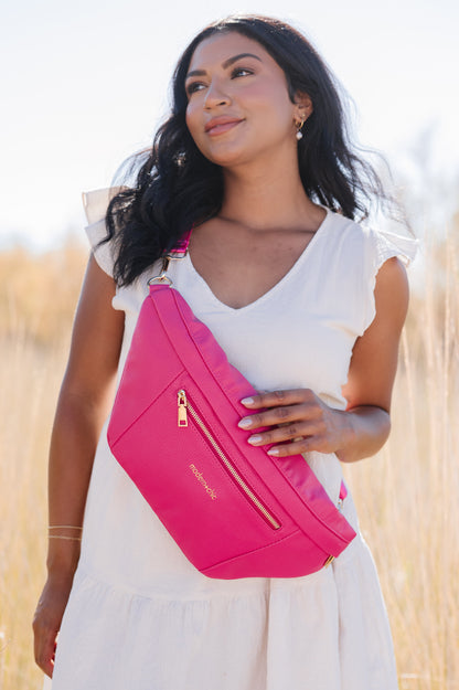 A woman wearing a white dress and a hot pink oversized Modern+Chic Presley Oversized Sling Bag for Women with gold hardware across her torso.