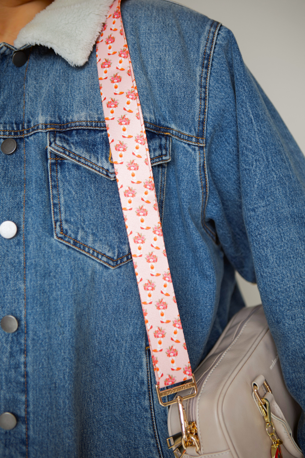 Pink cowboy boot and floral-patterned strap on a denim jacket and beige handbag