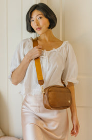 A woman wearing a brown crossbody bag.