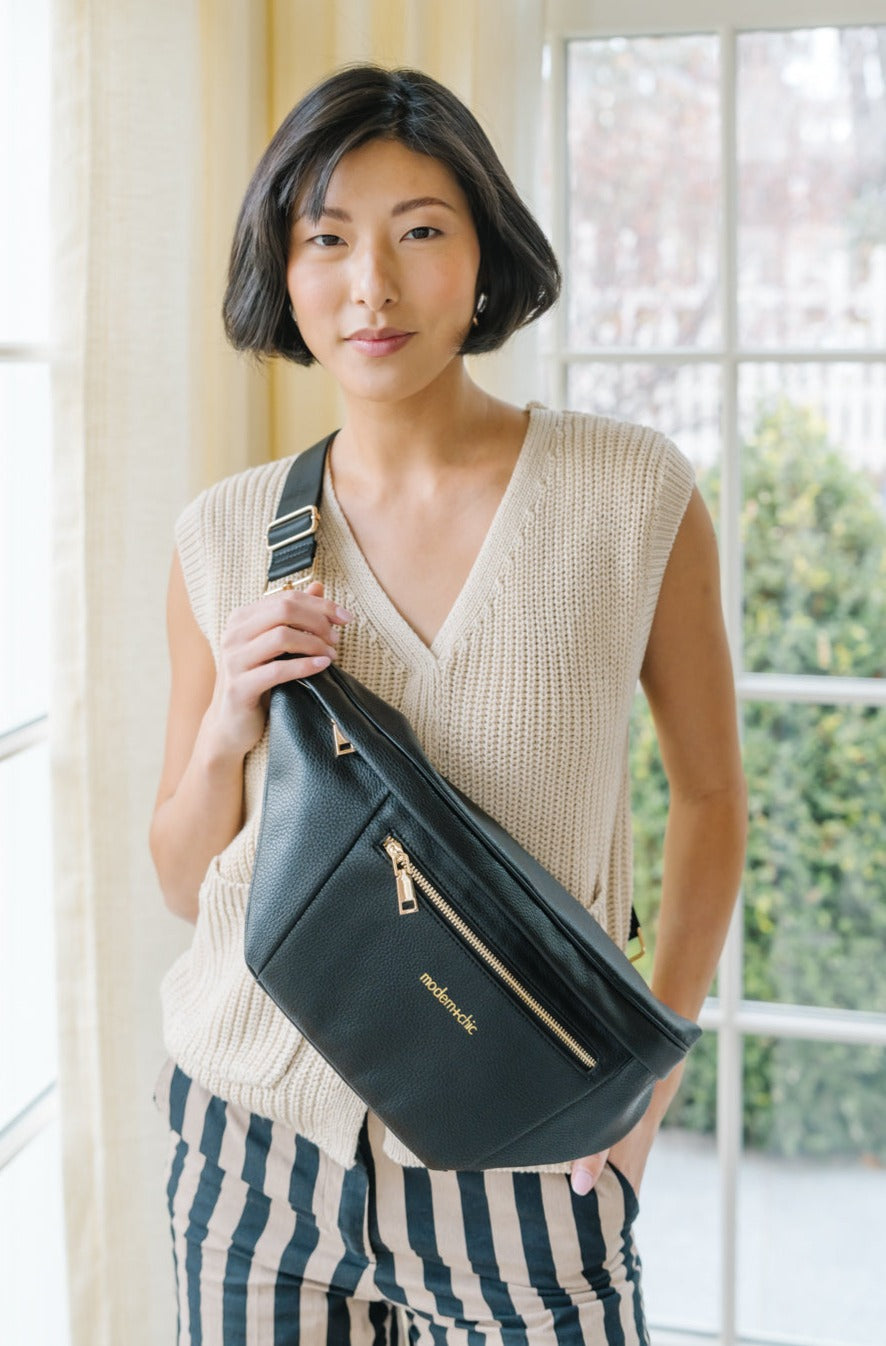 A woman wearing an oversized black sling bag.