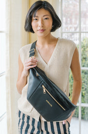 A woman wearing an oversized black sling bag.