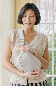 A woman wearing cream belt bag across her torso.