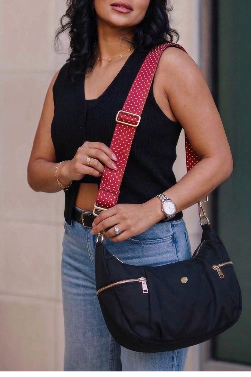 Woman holding a black Modern + Chic Parker Crescent Crossbody Bag for Women with a red polka dot strap.