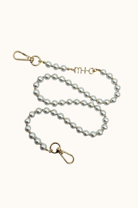 Pearl bag strap with gold clasp on a white background