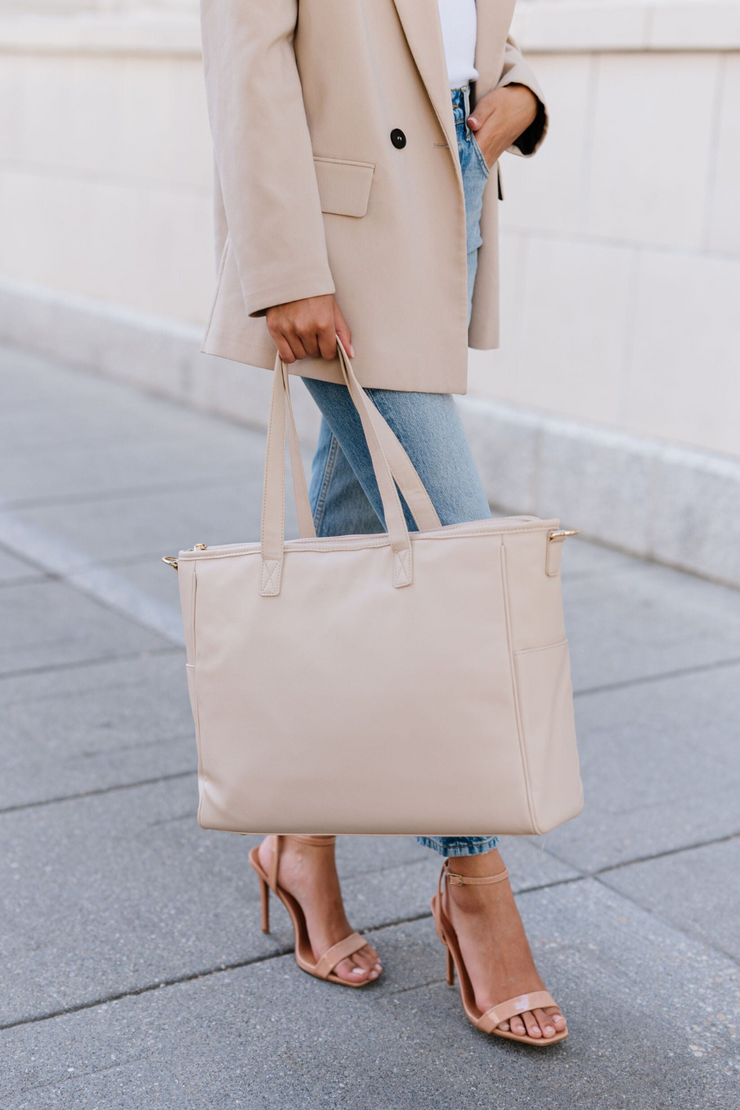 A woman holding a cream tote.