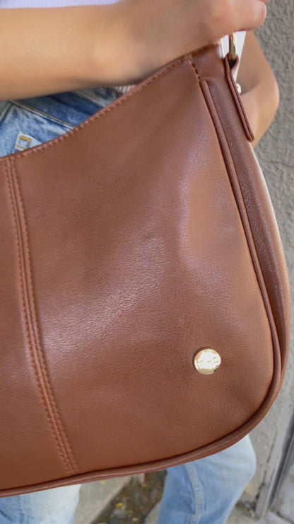 A video showing a mode posing with a variety of colors of a Modern + Chic Marissa vegan leather crossbody handbag.