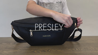 A woman showing the features and benefits of a Modern+Chic Presley Oversized Sling Bag for Women with gold hardware. 