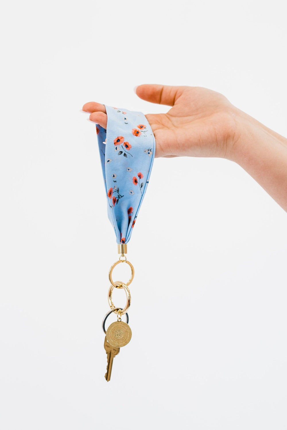 A hand holding Modern + Chic Luna Fabric Keychain Bracelet for Women in front of a white background.