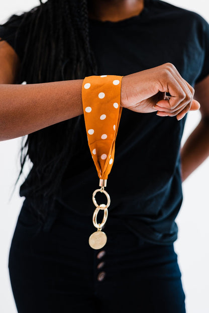 A woman wearing all black wearing an orange and white polka dot Modern + Chic Luna Fabric Keychain Bracelet for Women.