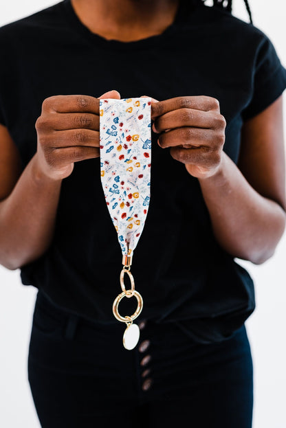A woman wearing all black holding a Modern + Chic Luna Fabric Keychain Bracelet for Women. 