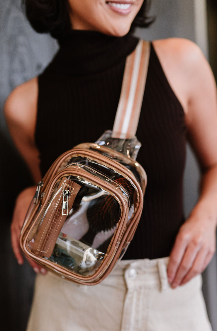 woman wearing clear sling crossbody bag with bronze vegan leather trim, striped strap