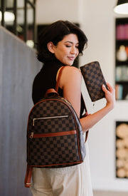 woman carrying a vegan leather dome backpack on one shoulder and holding a matching wallet