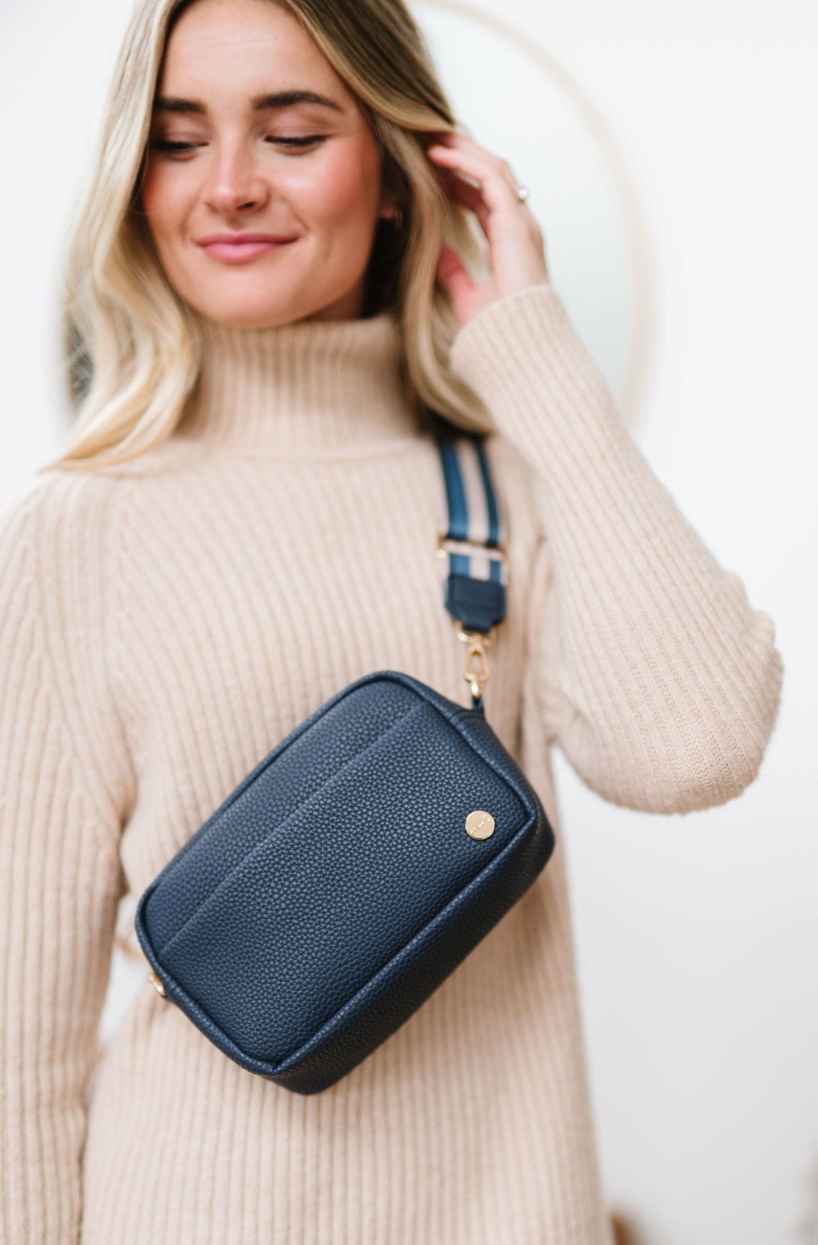 Woman wearing a blue Modern+Chic Willow Vegan Leather Convertible Crossbody Bag on a white background. 